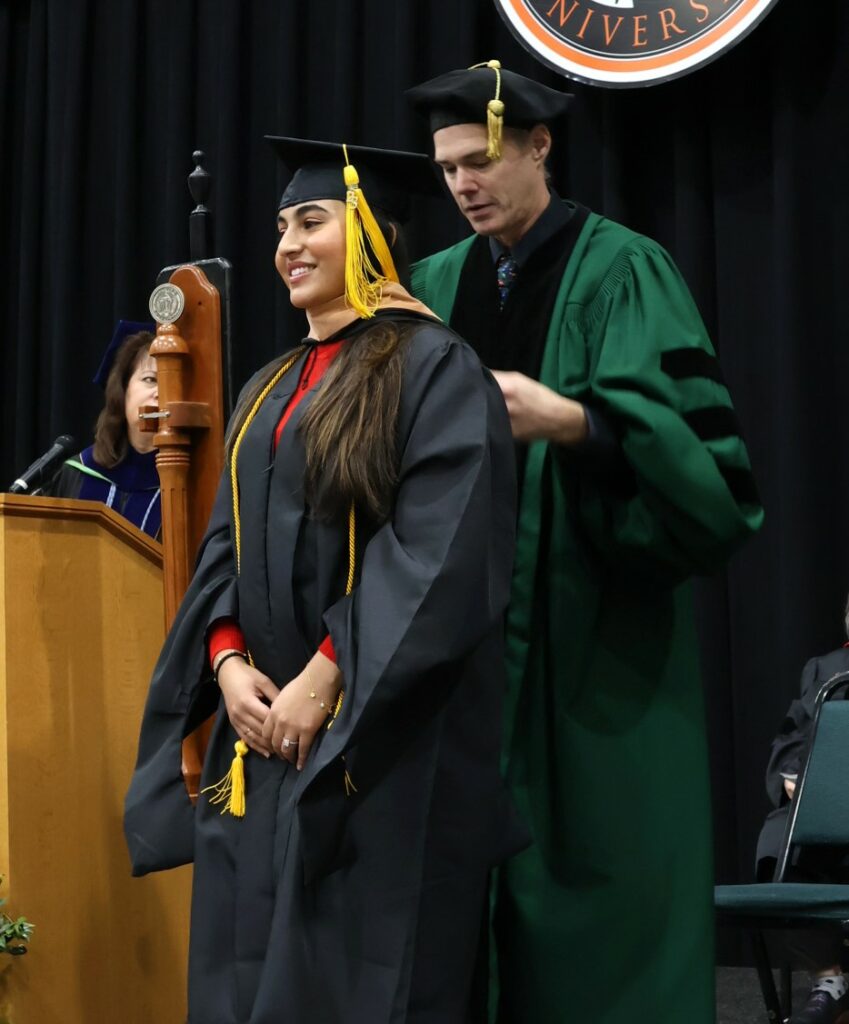 Dr. Kevin Hill, right, hoods a master's degree recipient at the 12-9-23 graduation ceremony.