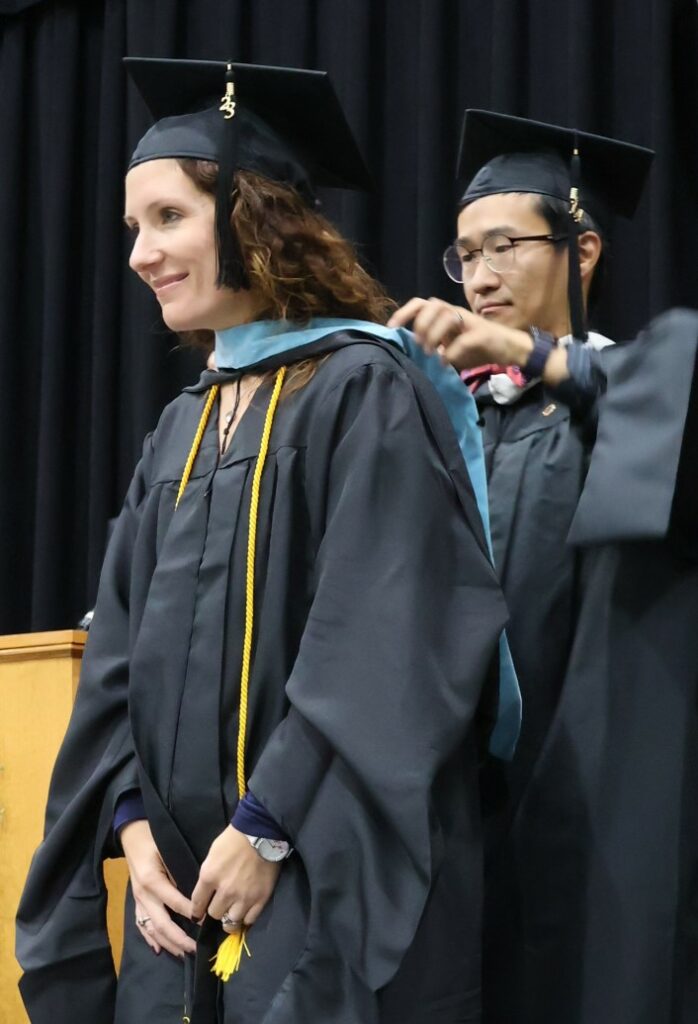 Dexter Lim, right, hoods a Master of Arts in Education graduate on 12-9-23.