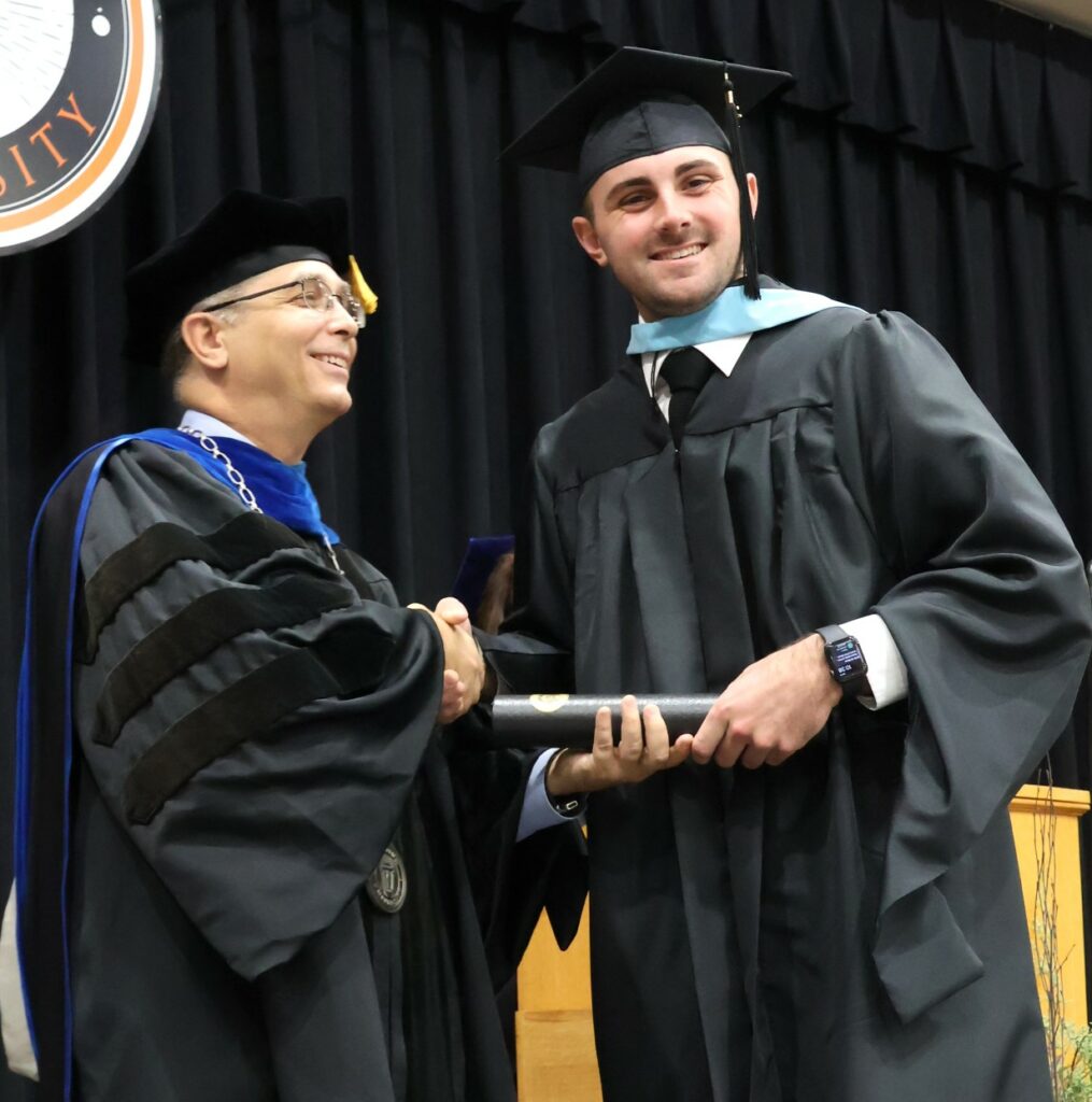 Dr. Scott Hummel congratulates a graduate on 12-9-23.