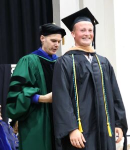 Dr. Kevin Hill, left, hoods Isak Holster, who earned a Master of Business Administration.