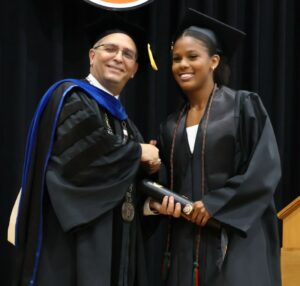 Graduate Taylor Sanders, right, shakes hands with Dr. Scott Hummel.