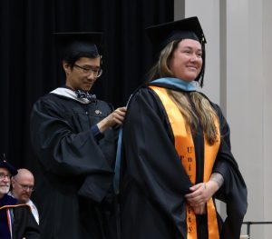 Dexter Lim, left, hoods a Master of Arts in Education degree recipient.