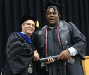 Jamicheal Wilson, right, shakes hands with Dr. Scott Hummel during graduation.