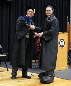 Todd Wallin, right, wears his mascot boots as he shakes hands with Dr. Scott Hummel, Tusculum’s president.