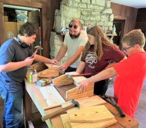 Children work with Dr. Peter Noll, second from left, during the Hand Tool Woodworking Camp in the summer.