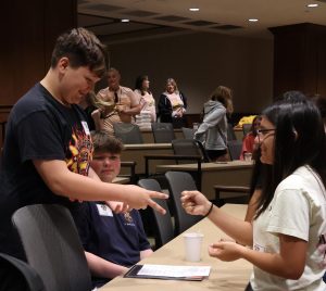 Two students participate in an ice-breaker game of Rock, Paper, Scissors.