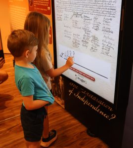 Harper Armstrong, right, signs the Declaration of Independence as her brother, Wade, watches.