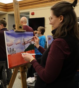Kim Fisher paints one of the trees in her Impressionist landscape.