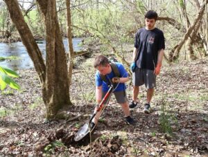 Tusculum student Clay Mendez, right, instructs Cub Scout Mason Dunn in digging a hole to plant a tree.