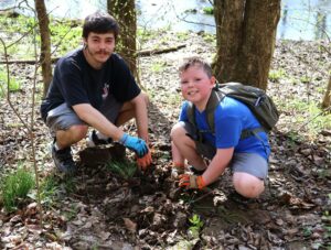 Tusculum student Clay Mendez, left and Cub Scout Mason Dunn put dirt around the seedling.
