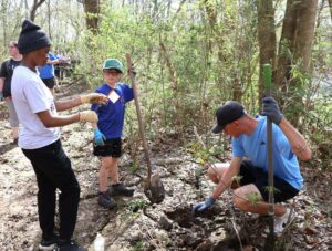 Left to right: Tusculum student Zothile Mbhamali, Cub Scout Lucas Hensley and Tusculum student Liam Van Deventer prepare to plant a tree.