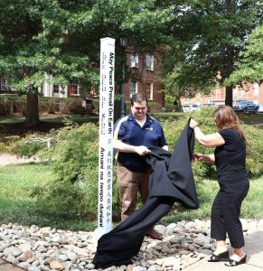 Brandon Farmer, left, and Lucia Fillers, the president and past president of the Rotary Club of Greeneville, unveil the peace pole.