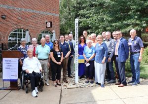 Rotary Club members stand by the peace pole.