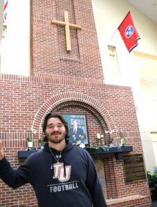 Student Nehemiah Storey stands under the cross in the Scott M. Niswonger Commons living room at Tusculum University.