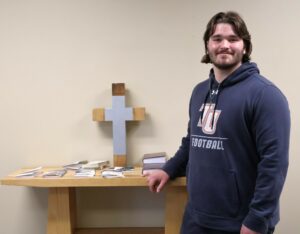 Student Nehemiah Storey stands by the cross in Tusculum’s chapel.