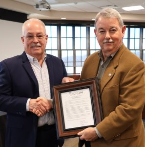 Dr. Greg Nelson, right, presents the resolution to Dale Long.