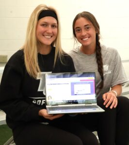Caylen Conrad, left, and Ellie Alvarez show the Brainingcamp platform on a laptop.