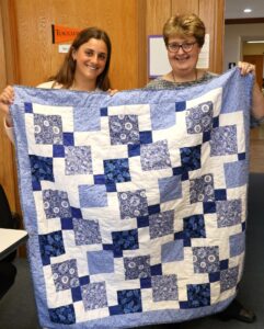 Student Sammy Jimenez, left, and Dr. Peggy Goodson-Rochelle, one of her professors, show the quilt.